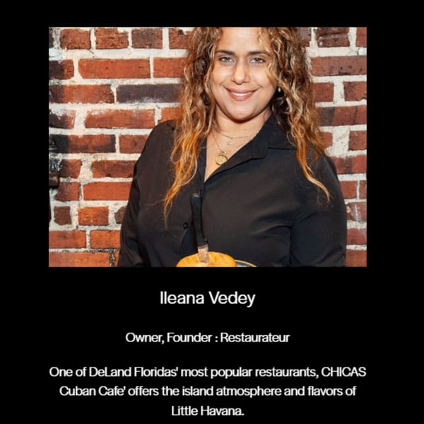 Ileana Vedey, owner of Chica's Cuban Cafe, smiling with a knife in a pumpkin against a brick wall.