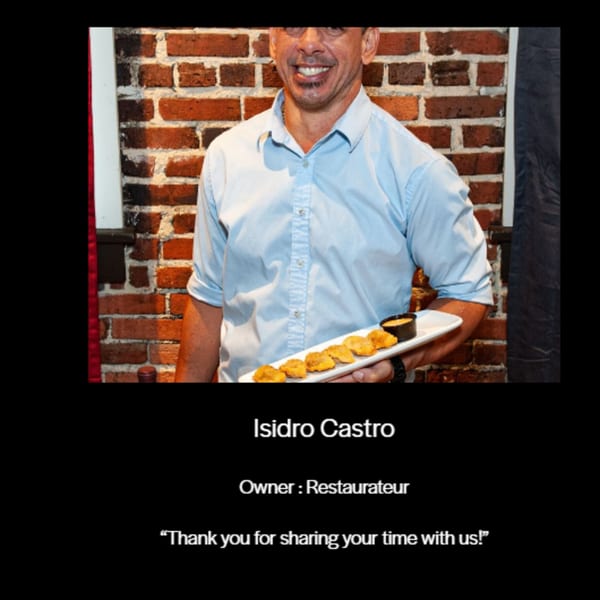 Isidro Castro, owner of Chica's Cuban Cafe, smiling and holding a plate of Cuban appetizers.